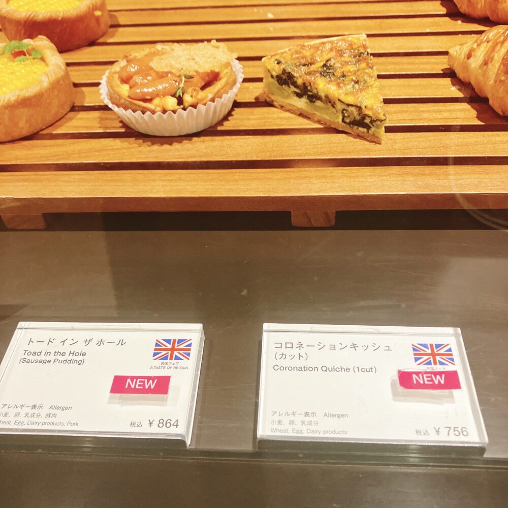 帝国ホテル東京の英国フェアで販売されている「トードインザホール」と「コロネーションキッシュ」のショーケース。それぞれの料理名と価格、アレルギー情報が書かれたPOPが見える。