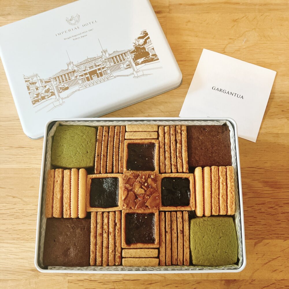 帝国ホテルのフランクロイドライト・プレミアムクッキー缶の蓋と中身。抹茶やココア、ジャムを挟んだものなど、10種類58個のクッキーが幾何学模様に美しく配置されている。