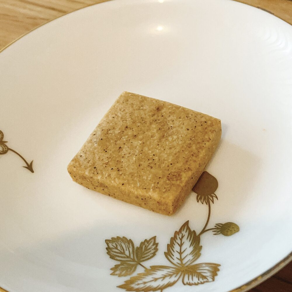 帝国ホテルのプレミアムクッキー缶に入っている、四角い黒豆きなこクッキー。きなこの粒が見える、ほろほろとした食感の和風サブレ。