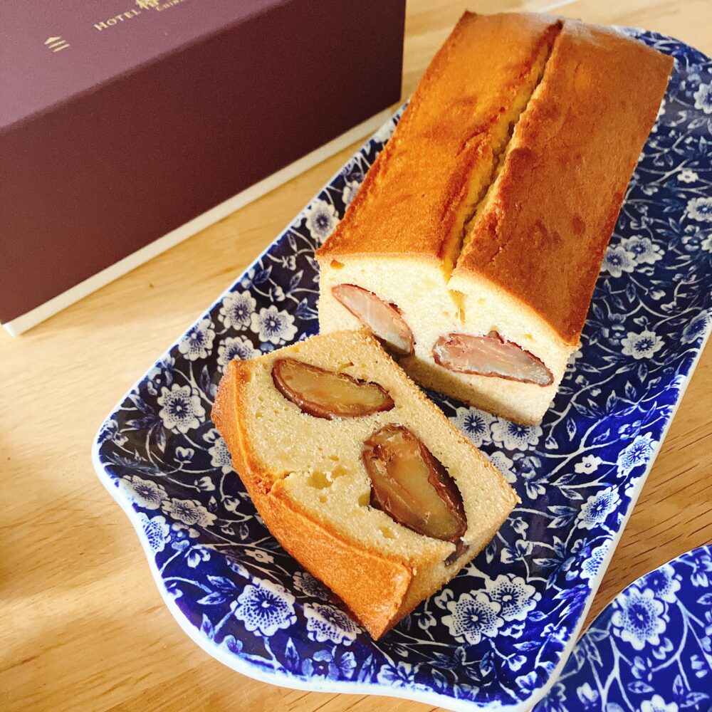 ホテル椿山荘東京の栗のパウンドケーキがカットされ、大きな渋皮栗の断面が白い生地から顔を覗かせている。手前の一切れと奥の残りのパウンドケーキが、青と白の模様の皿に置かれている。