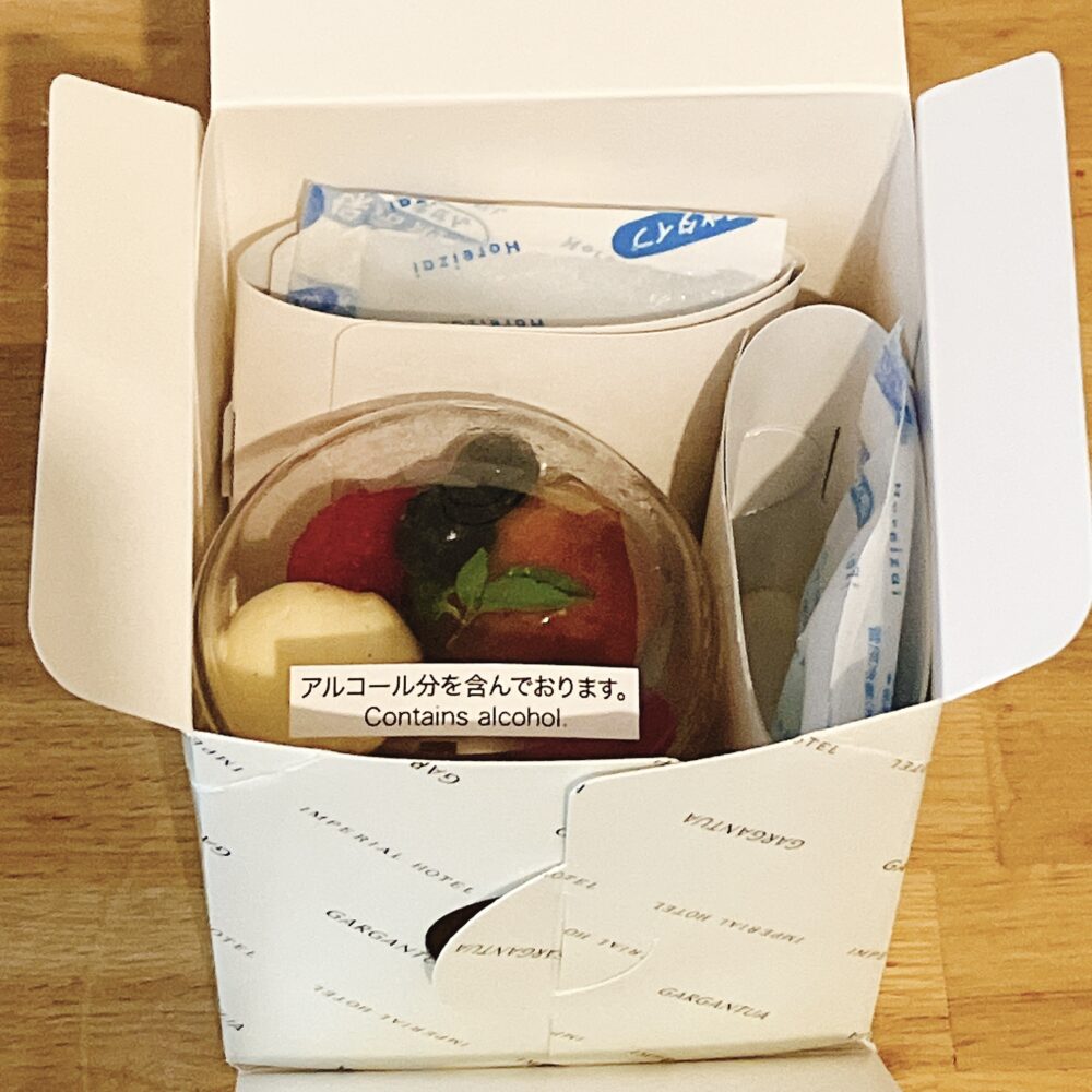 帝国ホテル ガルガンチュワのサヴァランの梱包内部。サヴァランのカップが専用の箱に固定され、上下に保冷剤が配置されている。「アルコール分を含んでおります」の注意書きシールが見える。