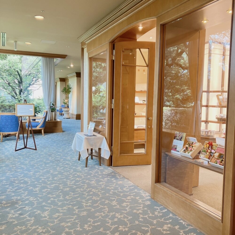 ホテル椿山荘東京・ホテルショップ「セレクションズ」の外観。青いカーペットが敷かれたホテル棟3階の通路に面しており、ガラス扉越しにお土産品が見える。