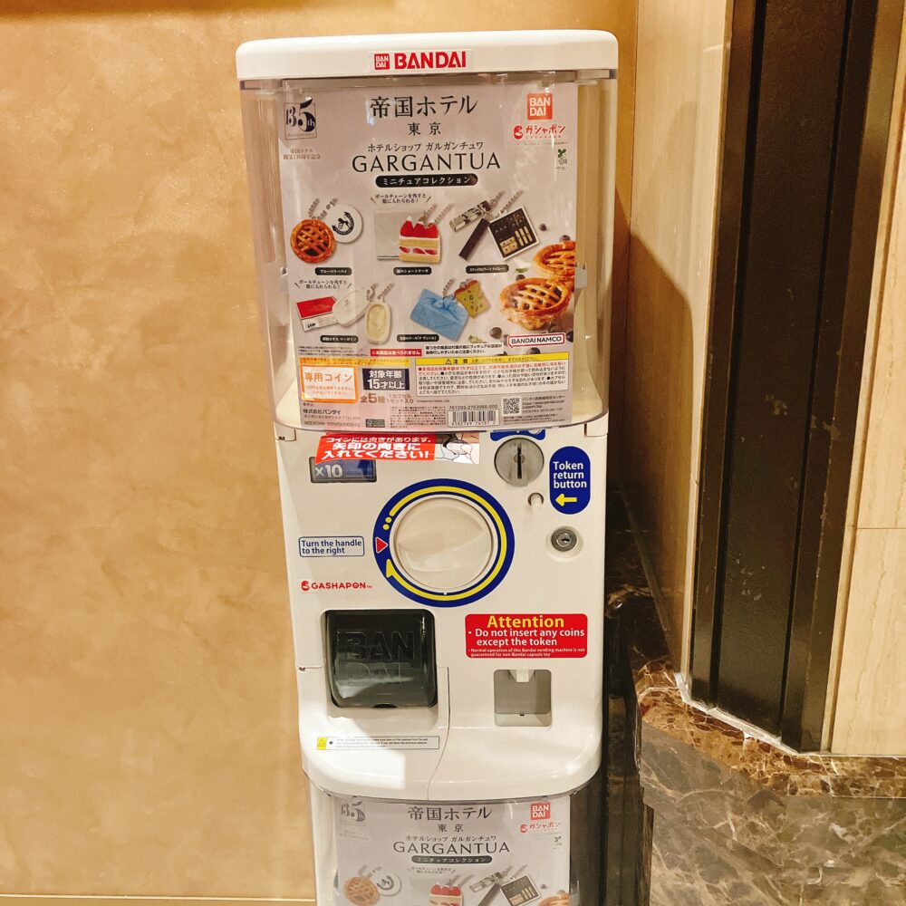 帝国ホテル ガルガンチュワのガチャポン筐体全体像。専用コイン投入口があり、「ガチャポンを回す」という表記とBANDAIのロゴが見える。