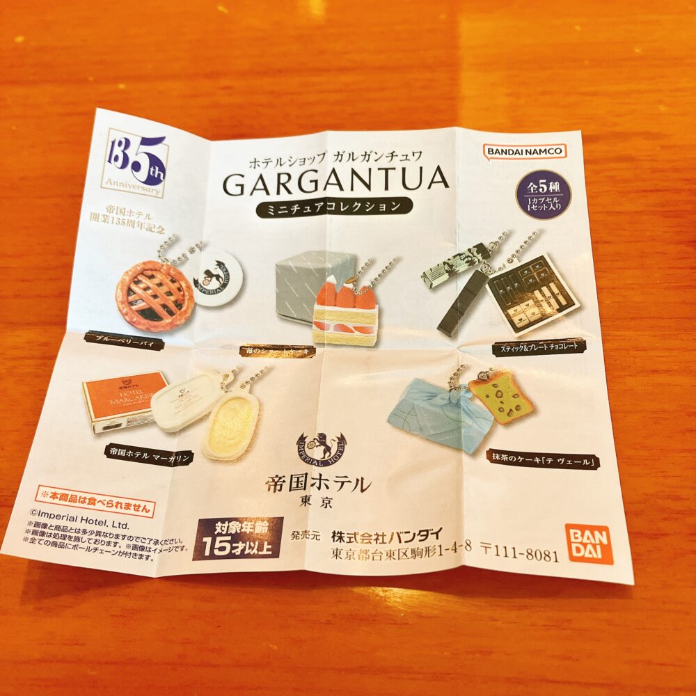 ホテルショップ ガルガンチュワ ミニチュアコレクションの説明書。開業135周年記念と記載されており、ブルーベリーパイ、ストロベリーショートケーキ、スティックチョコレート、帝国ホテルマーガリン、抹茶のケーキ（ラ・ヴェール）の全5種が写っている。