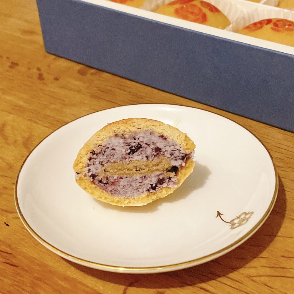 帝国ホテル 135周年記念のバターサンドを半分にカットした断面。紫色のブルーベリーバタークリーム、その中央に挟まれたシナモン風味のスポンジ生地、さらに黒いブルーベリーの粒が見える。