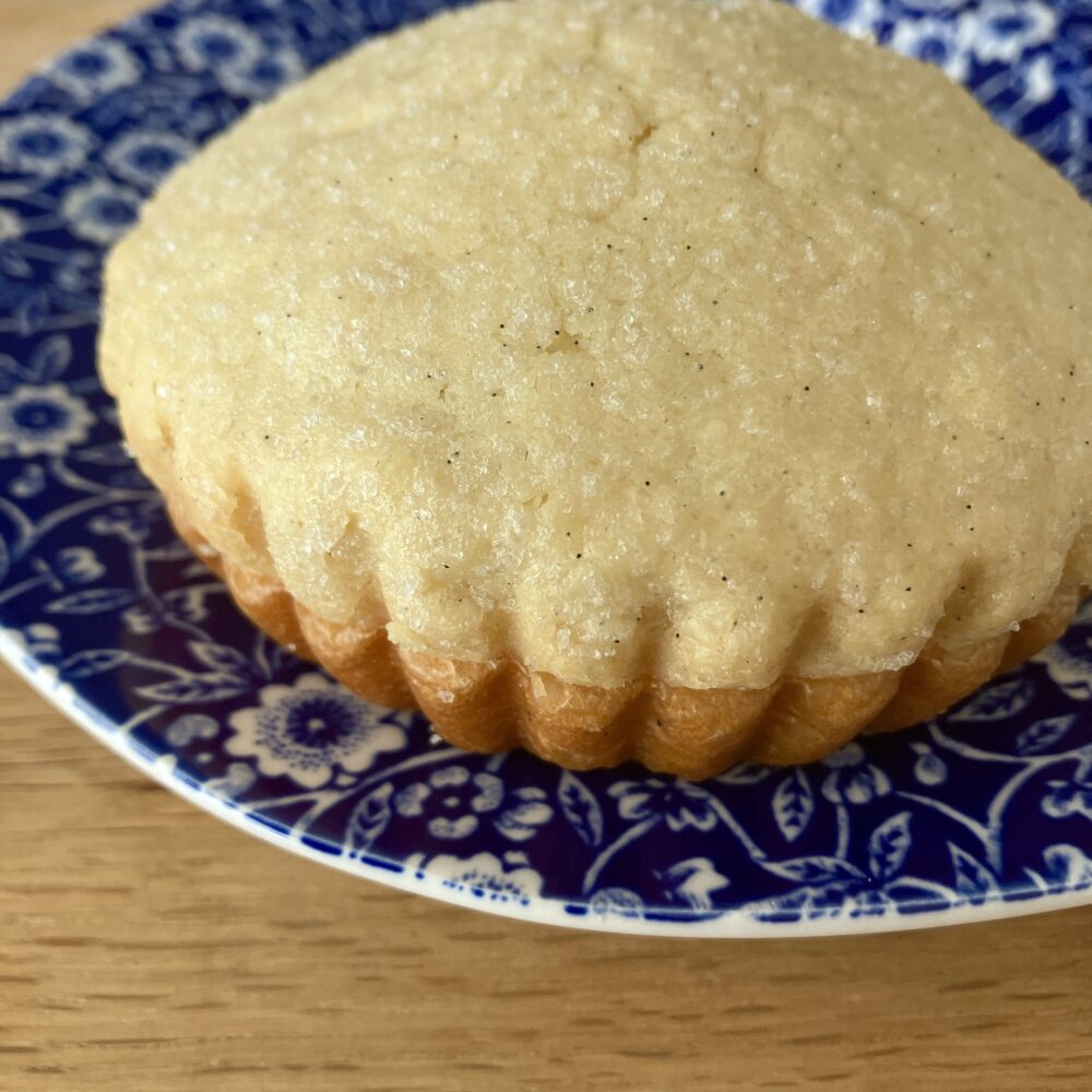 帝国ホテルのメロンパンのクローズアップ。バニラビーンズらしき黒い粒が見える、上部のリッチなクッキー生地と、下のふっくらしたパン生地の二層構造がはっきりと写っている。