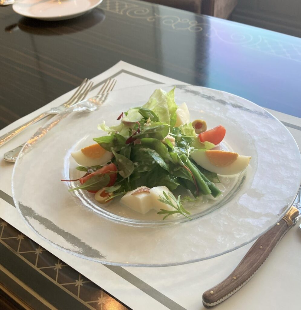 ガラスの器に美しく盛り付けられた帝国ホテルのニース風サラダ。ゆで卵、インゲン、トマト、ツナなどが鮮やかに配置されている。