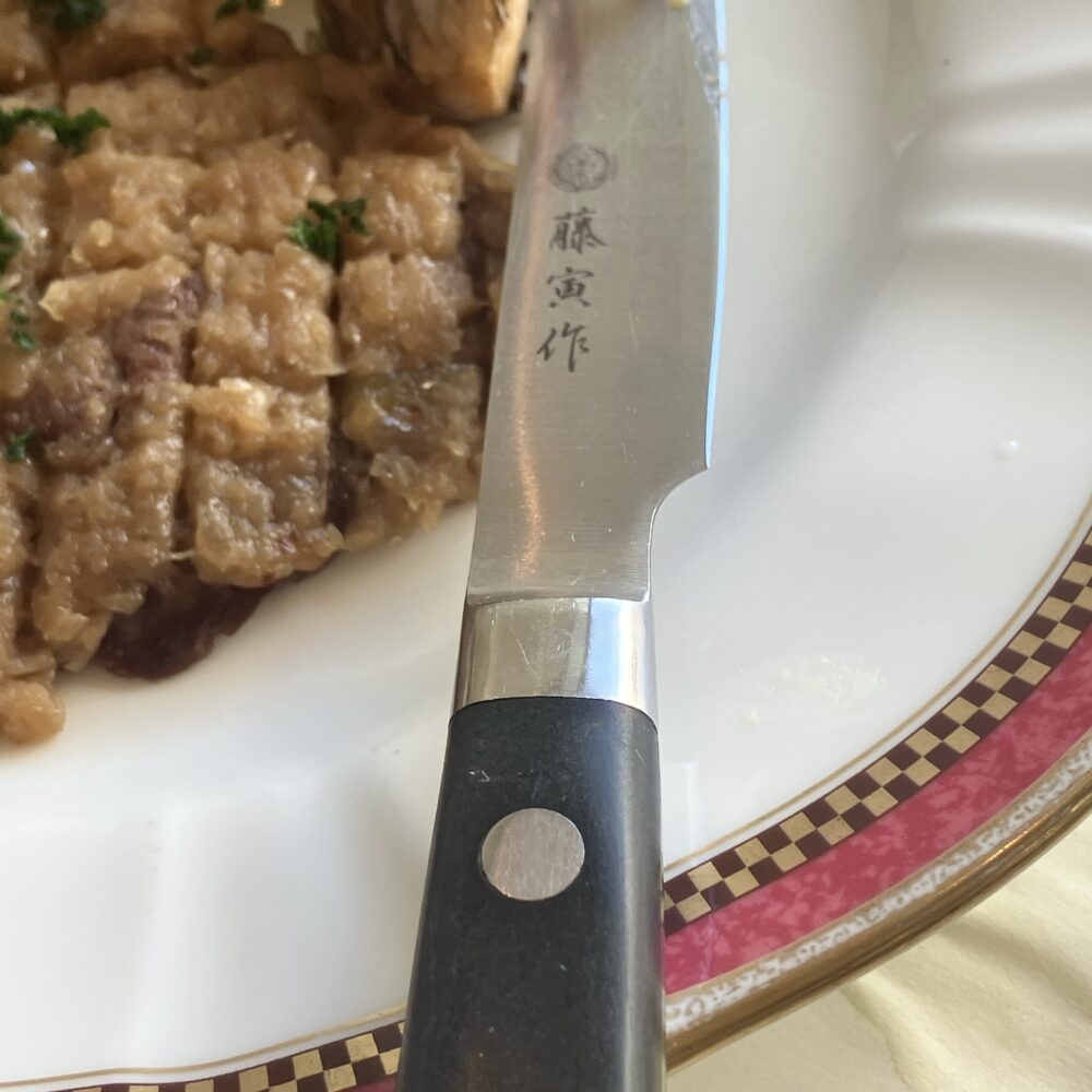 帝国ホテルのシャリアピンステーキの皿に添えられた「藤寅作」の刻印が入ったステーキナイフのアップ。