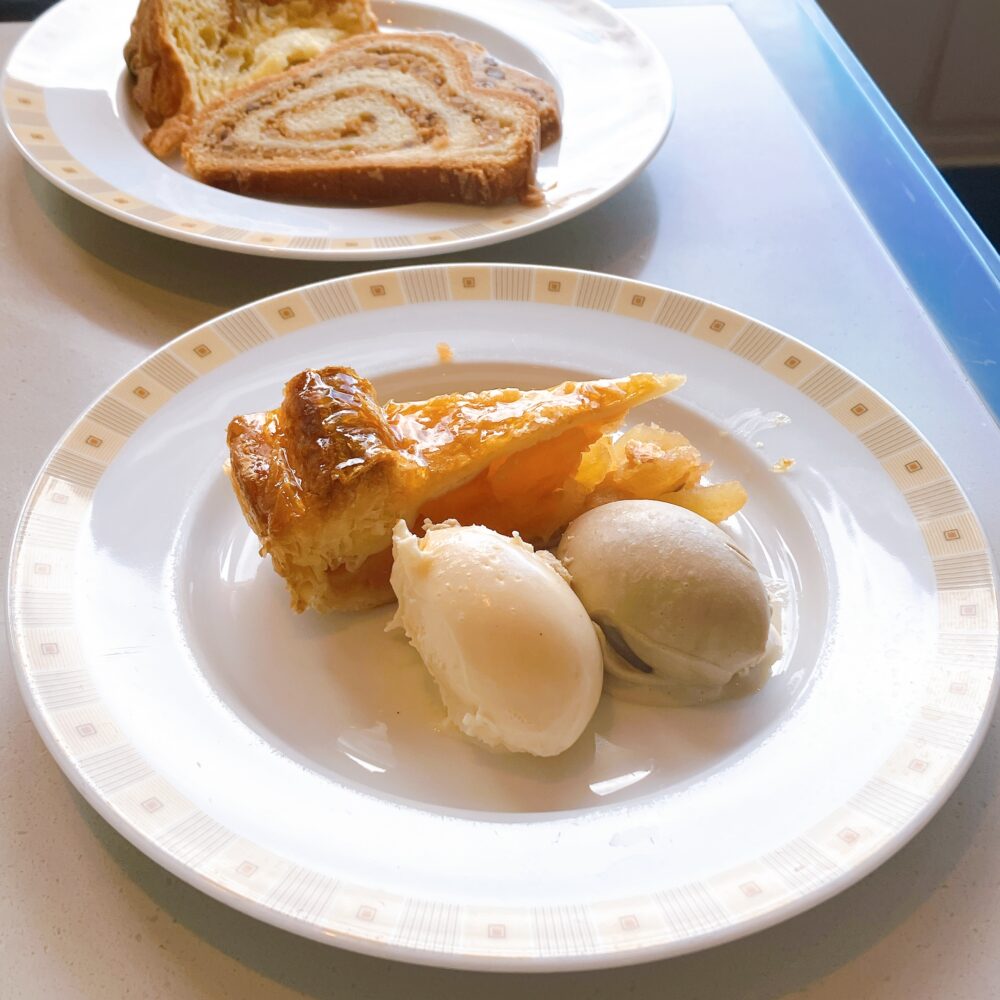 帝国ホテル「インペリアルバイキング サール」で、クリスマス限定ケーキの盛り合わせ、ジェラートを添えたアップルパイ、伝統のシュトレンとパネトーネが並んだデザートタイムのテーブルの様子。