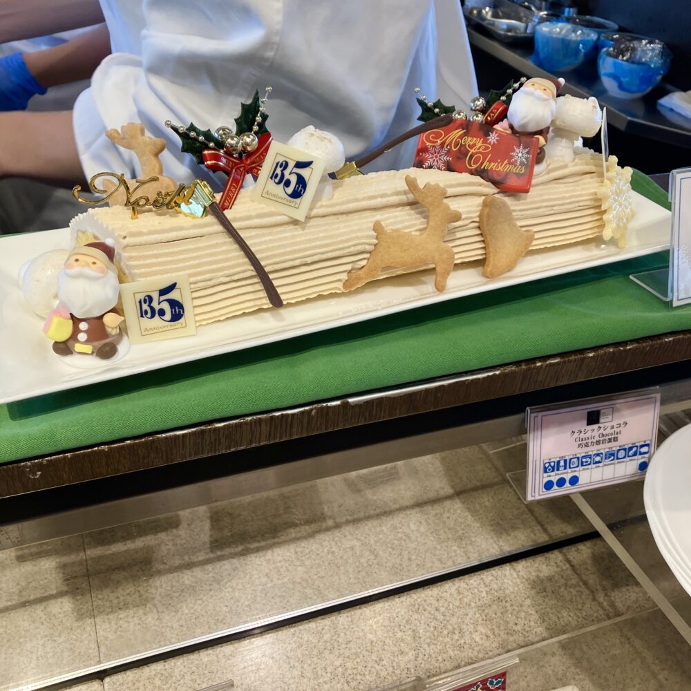 帝国ホテル135周年のロゴが飾られた、2025年クリスマス限定のキャラメル味のブッシュ・ド・ノエル。