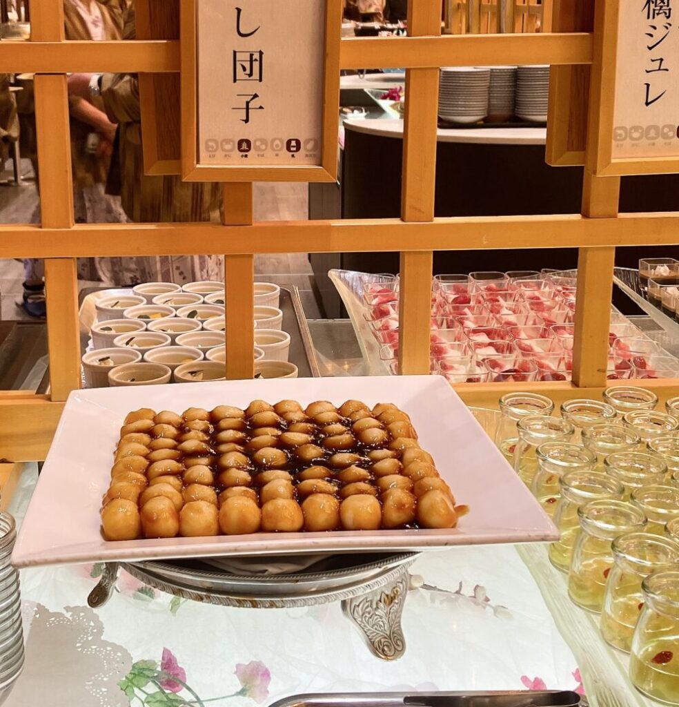 デザートコーナーに山盛りに並べられたみたらし団子と「みたらし団子」のメニュー札。