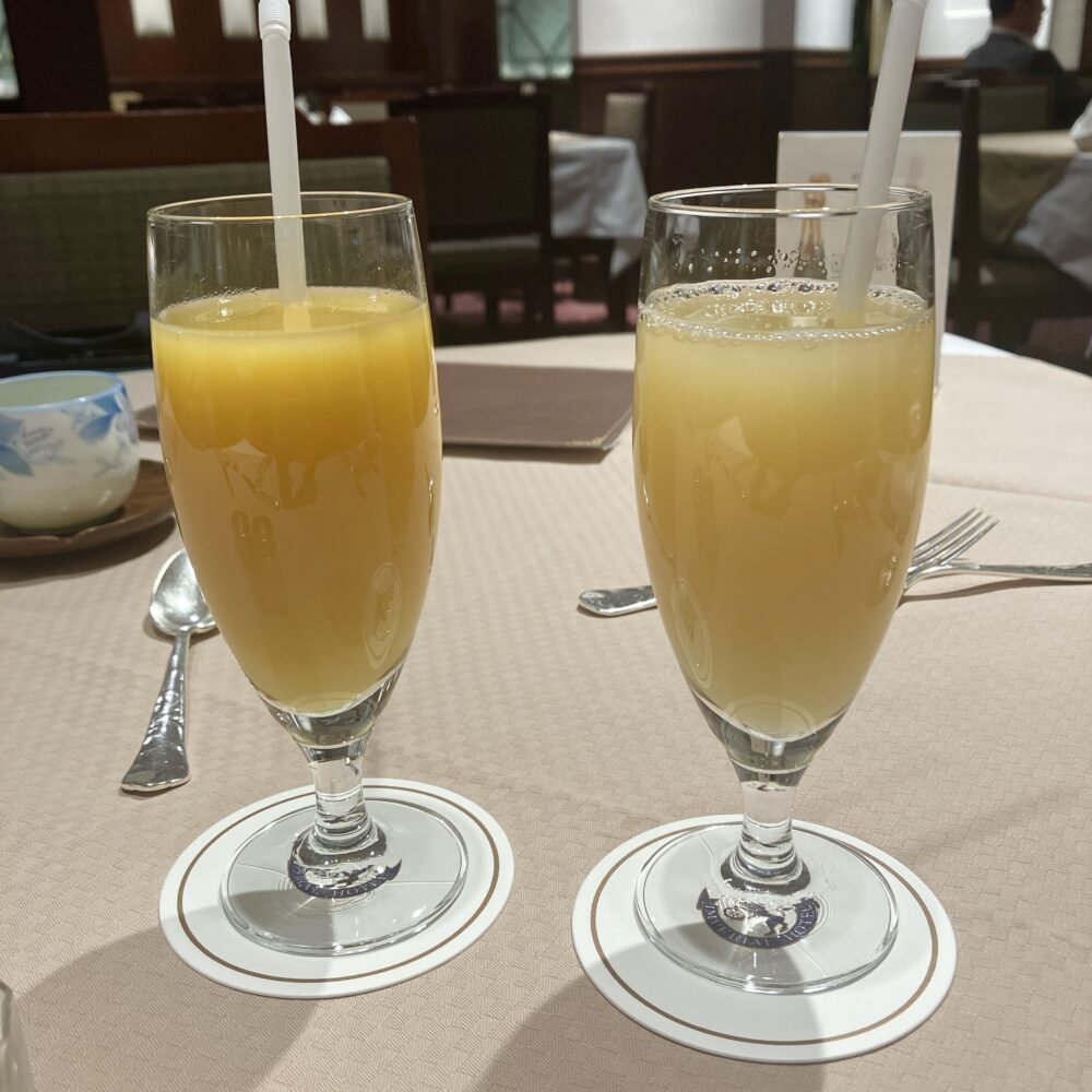 日本橋高島屋特別食堂で提供されるインペリアルクラブ会員特典のワンドリンク。帝国ホテルのロゴ入りコースターに乗ったオレンジジュースとりんごジュース。