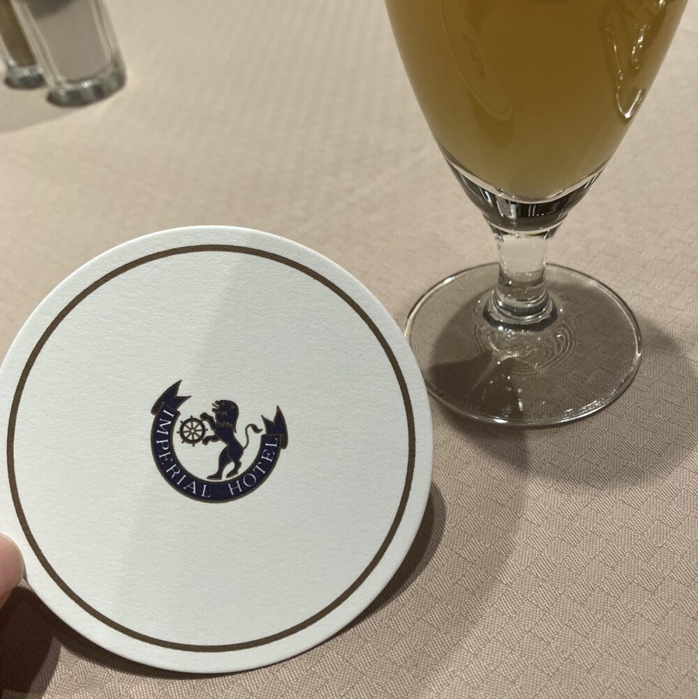 帝国ホテルのライオンロゴが入った紙コースターに乗せられた、オレンジジュースとりんごジュースの下に敷いてあった。