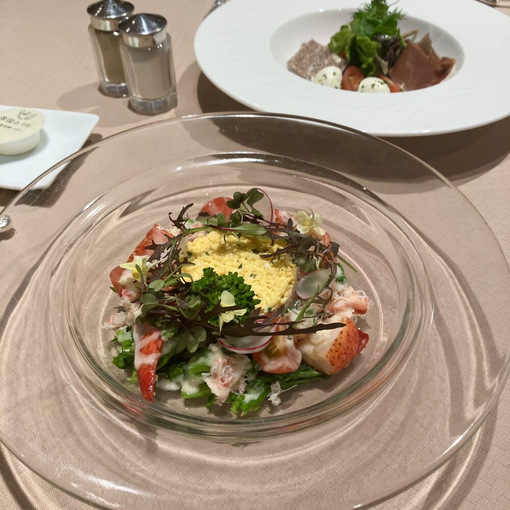 特別食堂の追加メニュー「紅ズワイガニのポテトサラダ」。中央のミモザ風ポテトサラダを囲むように、紅ズワイガニの身とハーブが花輪（リース）状に美しく配置されている。