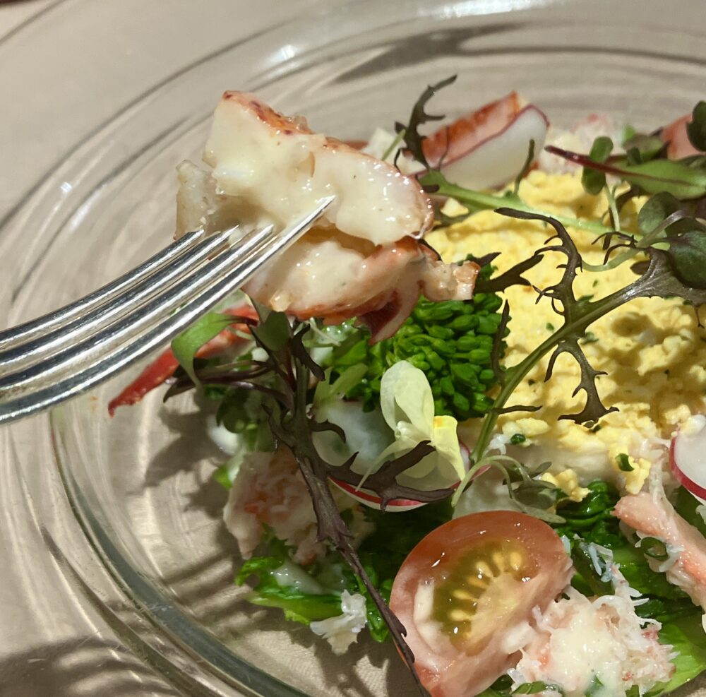 紅ズワイガニのポテトサラダの蟹の身をフォークで持ち上げている接写。繊維がしっかりした肉厚な蟹肉とドレッシングが絡み合い、プラス900円の価値があることを証明している。