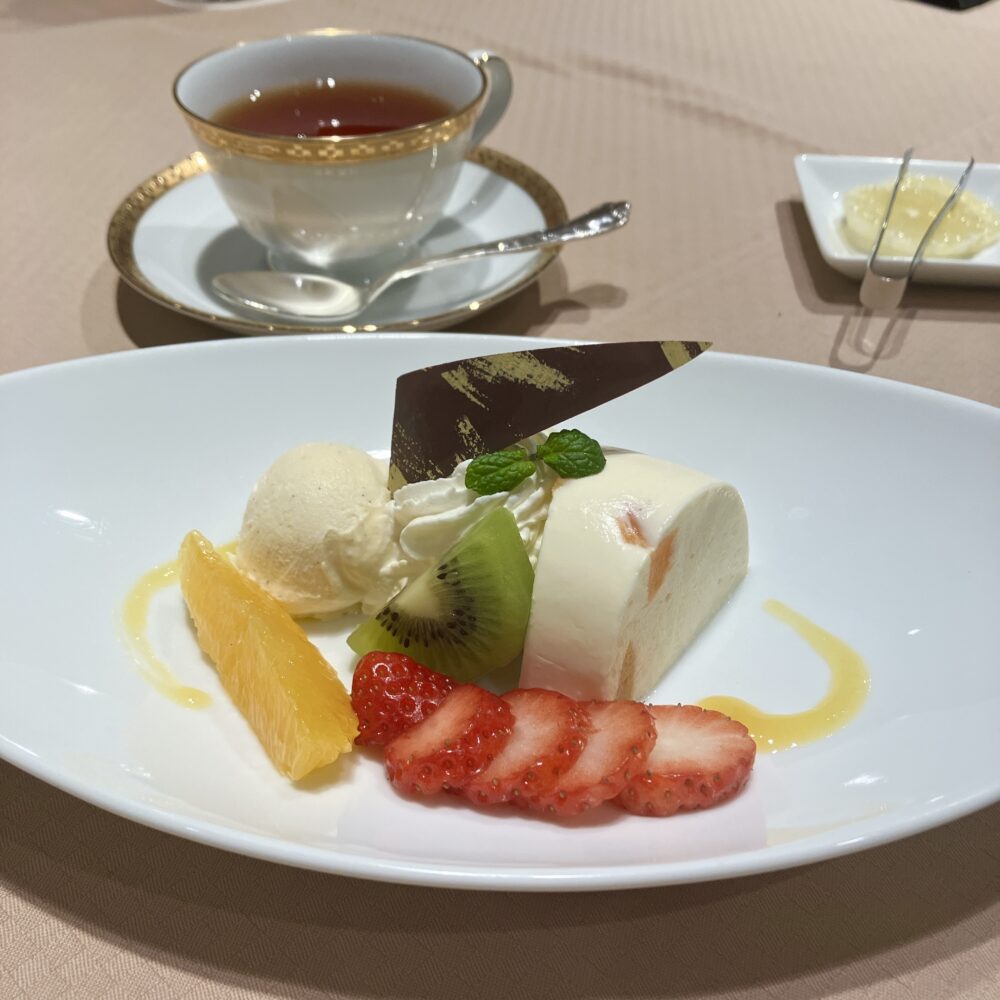 故・村上信夫初代総料理長が考案した「インペリアルババロア」。白いババロアの中に刻んだアプリコットが見え、バニラアイスとフルーツ（苺、キウイ、オレンジ）、チョコレートが添えられた伝統的な盛り付け。