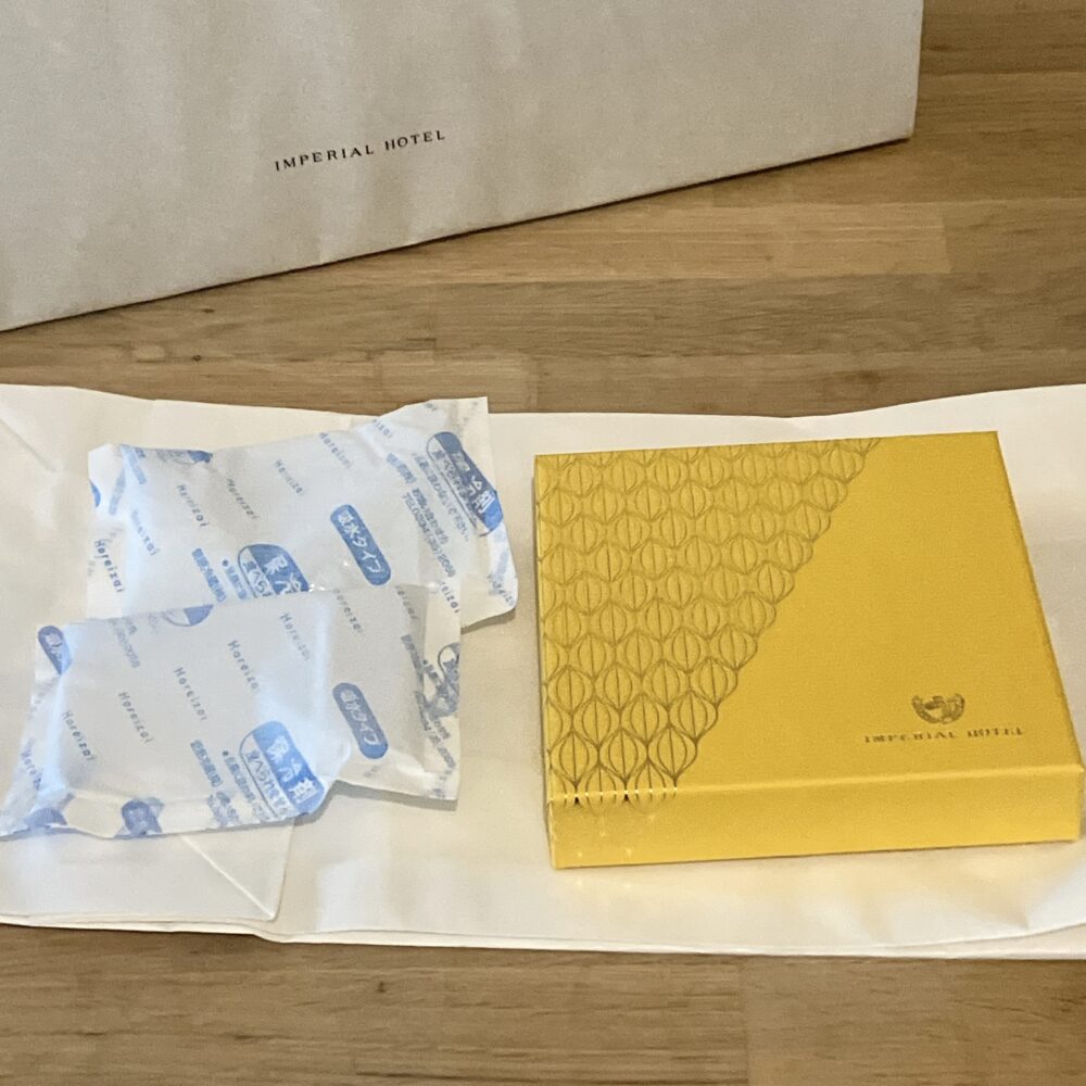 黄色いボンボンショコラの箱と、同梱されていた2つの保冷剤。箱から出した後も品質を保つための配慮が見える。