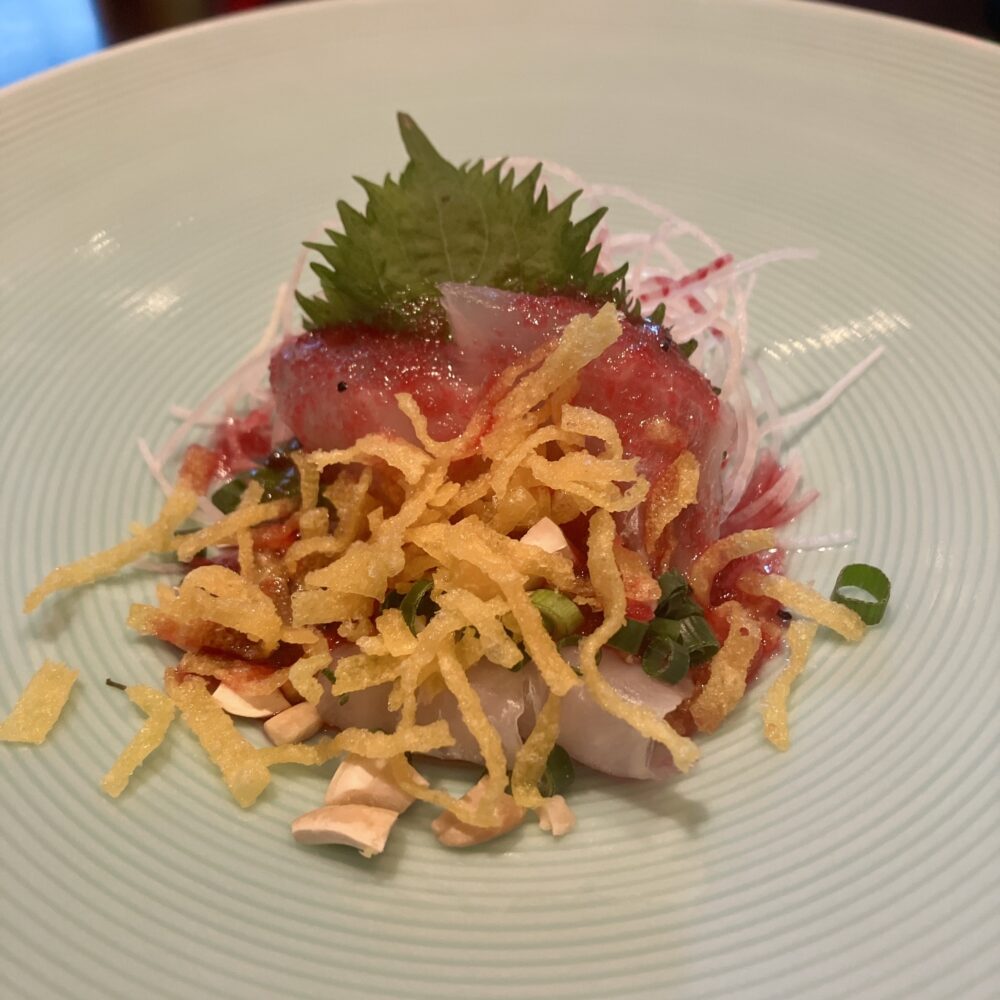 真鯛の切り身の上に赤いソースとパリパリとした黄色い揚げ物が乗った、チャイナルームの真鯛のチャイニーズサラダ。