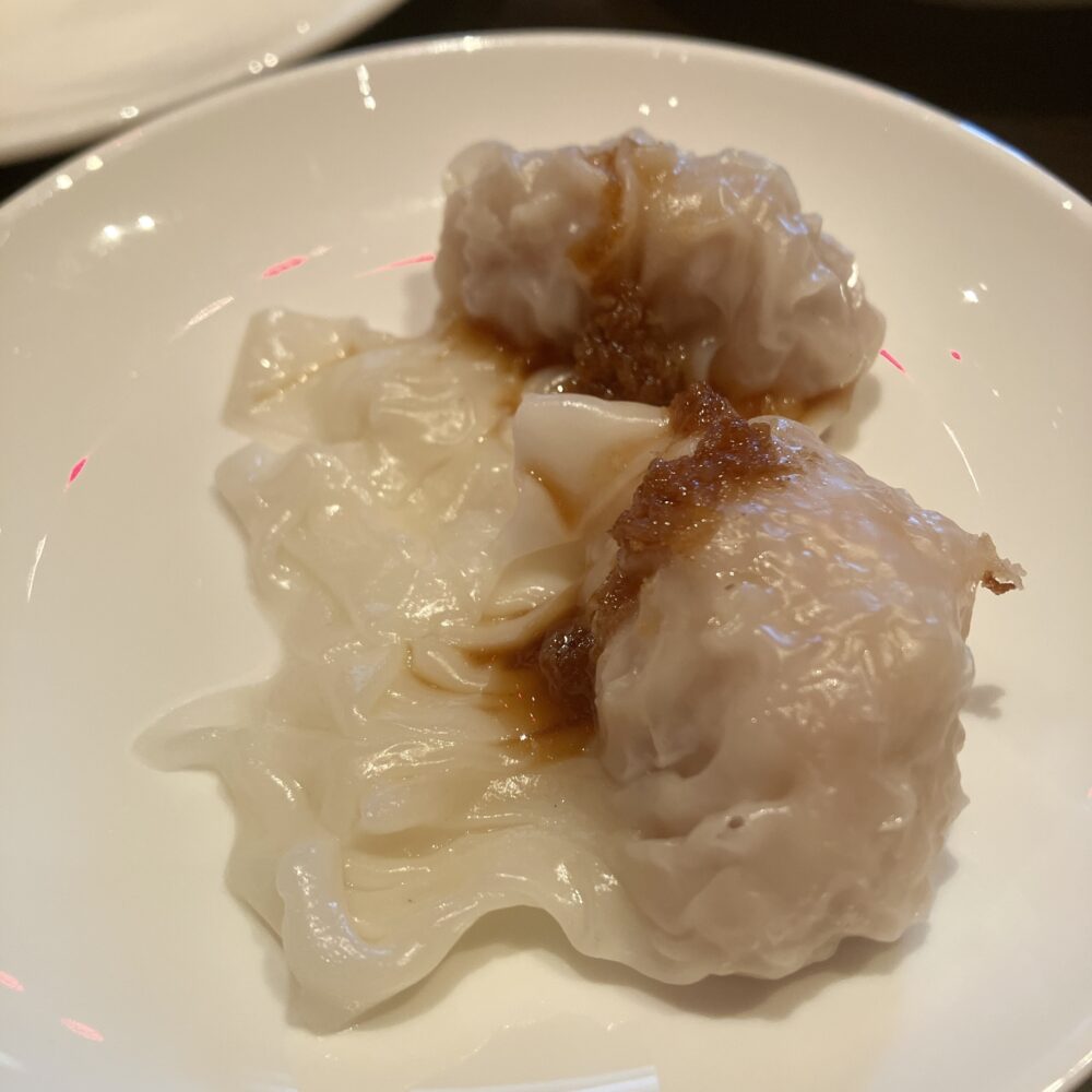 白い皿に盛り付けられた「エビ 豚肉の茹でワンタン」。つるんとした皮のワンタンに、旨味たっぷりのピリ辛ダレ（紅油）がかかっている様子｜チャイナルーム