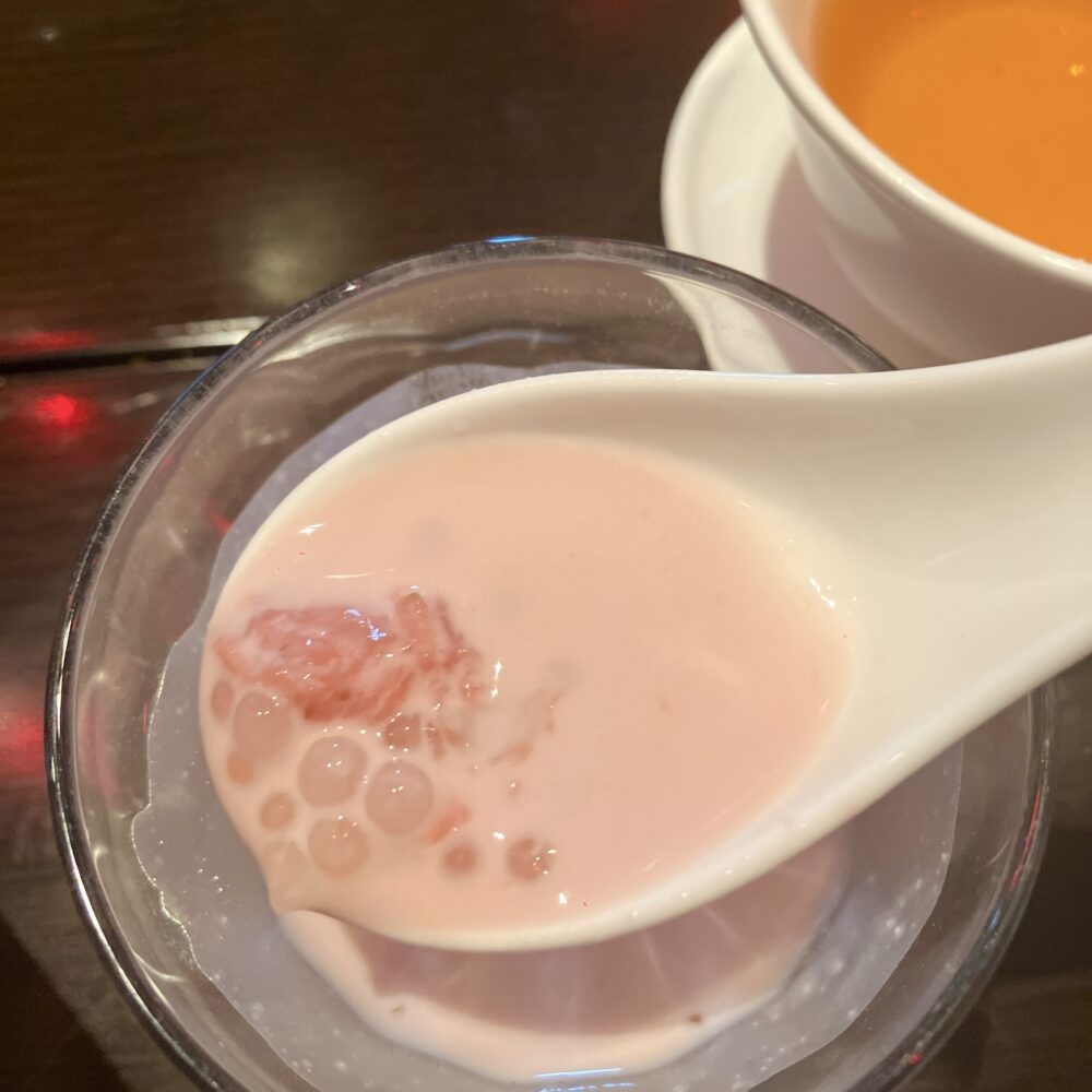 グラスに入ったチャイナルームのデザート。レンゲですくわれたピンク色のイチゴ風味タピオカココナッツミルク。