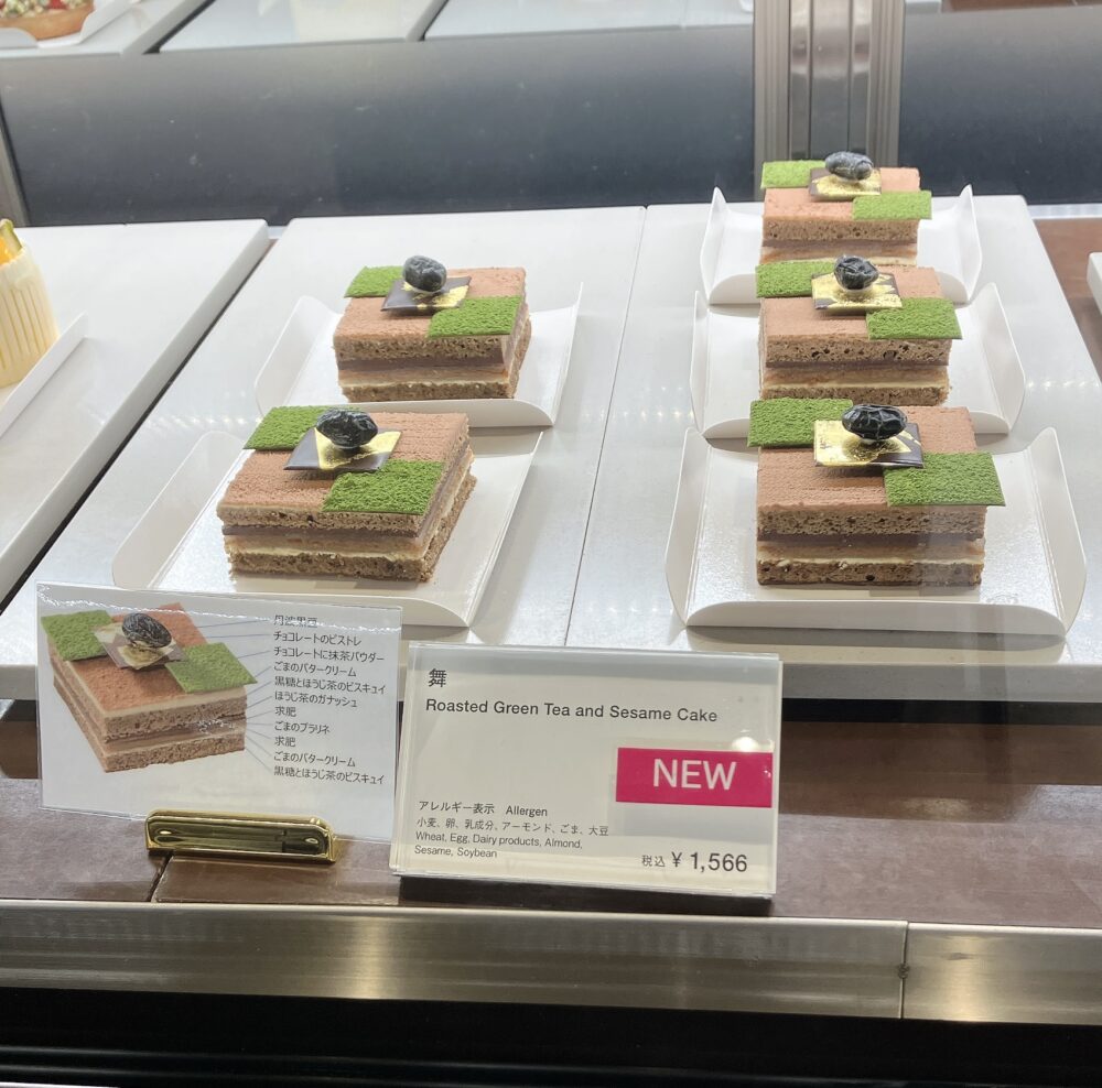 ガルガンチュワのショーケースに並ぶ新作ケーキ「舞」。ほうじ茶のブラウンの層に、苔庭のような鮮やかな緑色の抹茶パウダーと黒豆がトッピングされている。