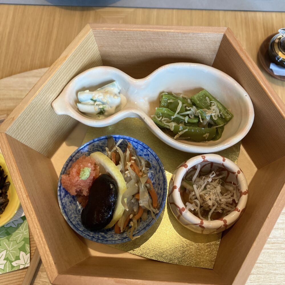 帝国ホテル京都の和食朝食（お重箱の上段）。三つ葉のお浸しやじゃこ万願寺など、色鮮やかな小鉢の盛り合わせ