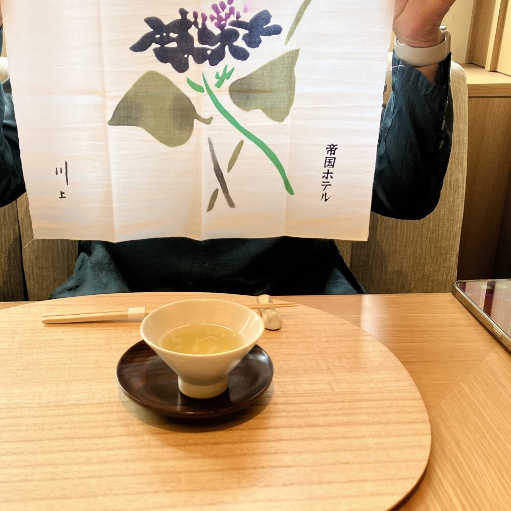 帝国ホテル京都の和食朝食で最初に提供される温かいお茶と、持ち帰り可能な「祇園 川上」の名前入り特製手ぬぐい