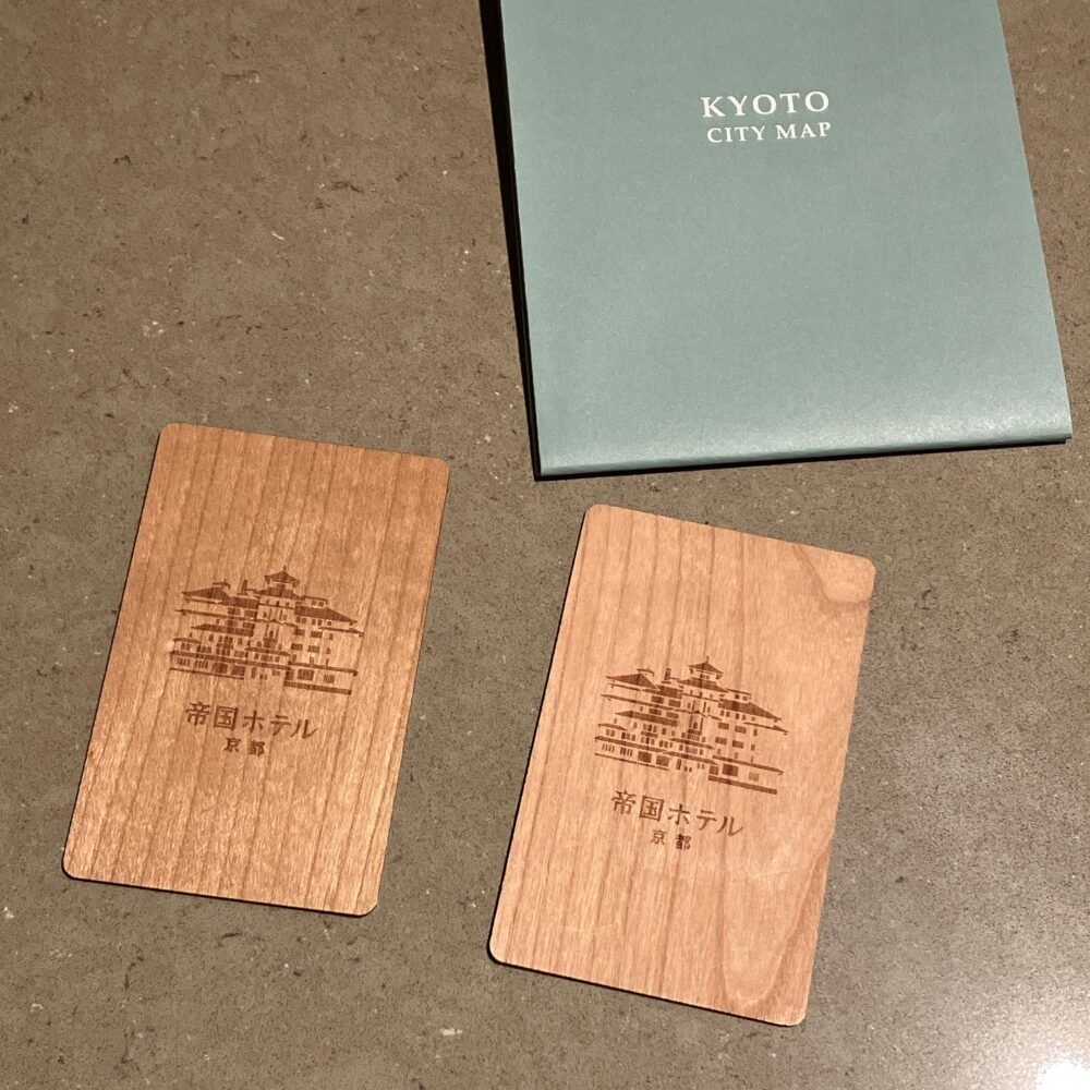 帝国ホテル京都の特製木製ルームキー。ホテルの外観が精密に彫刻されており、京都のシティマップと共に置かれている