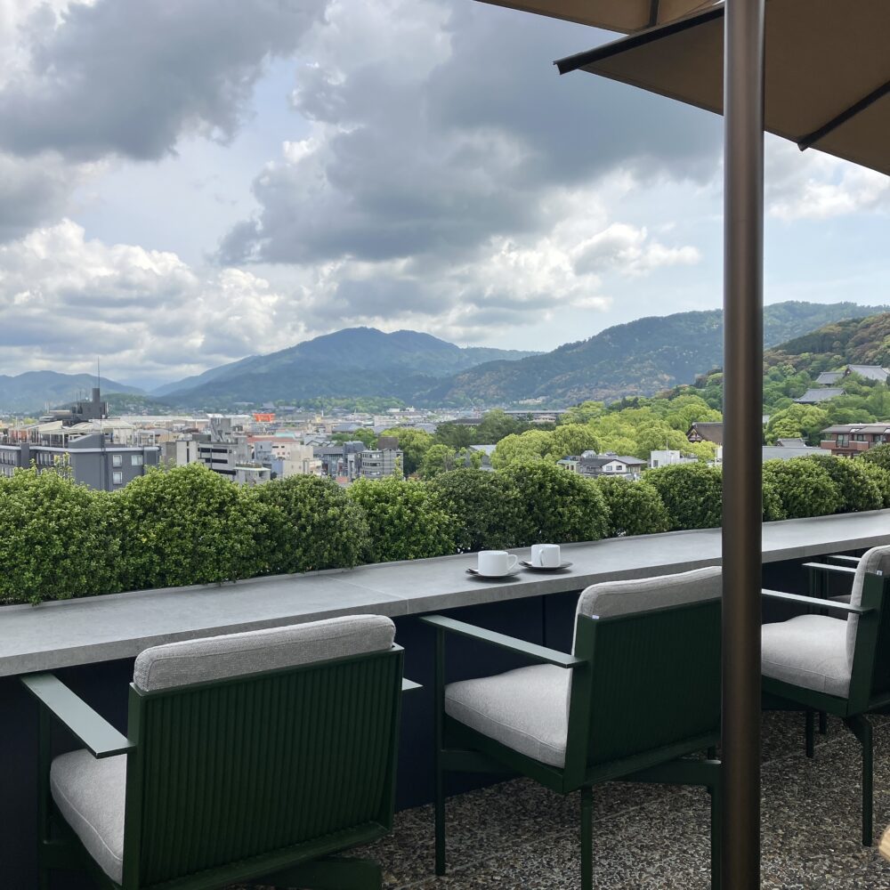 帝国ホテル京都のルーフトップバーのカウンター席から見た、昼間の山の景色。手前には、空のティーカップが2つ置かれている。