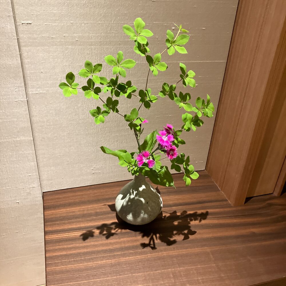 お部屋に飾られた季節の美しい生け花(一輪挿し)。木の家具に映える可憐な花