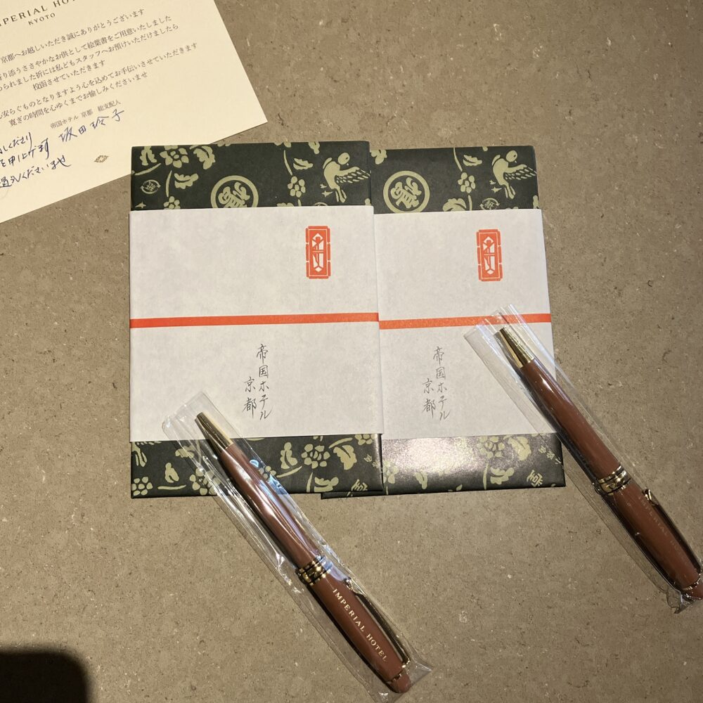帝国ホテル京都のデスクに置かれた総支配人からの直筆ウェルカムレターと、お土産にできるオリジナルロゴ入りボールペン・メモ帳