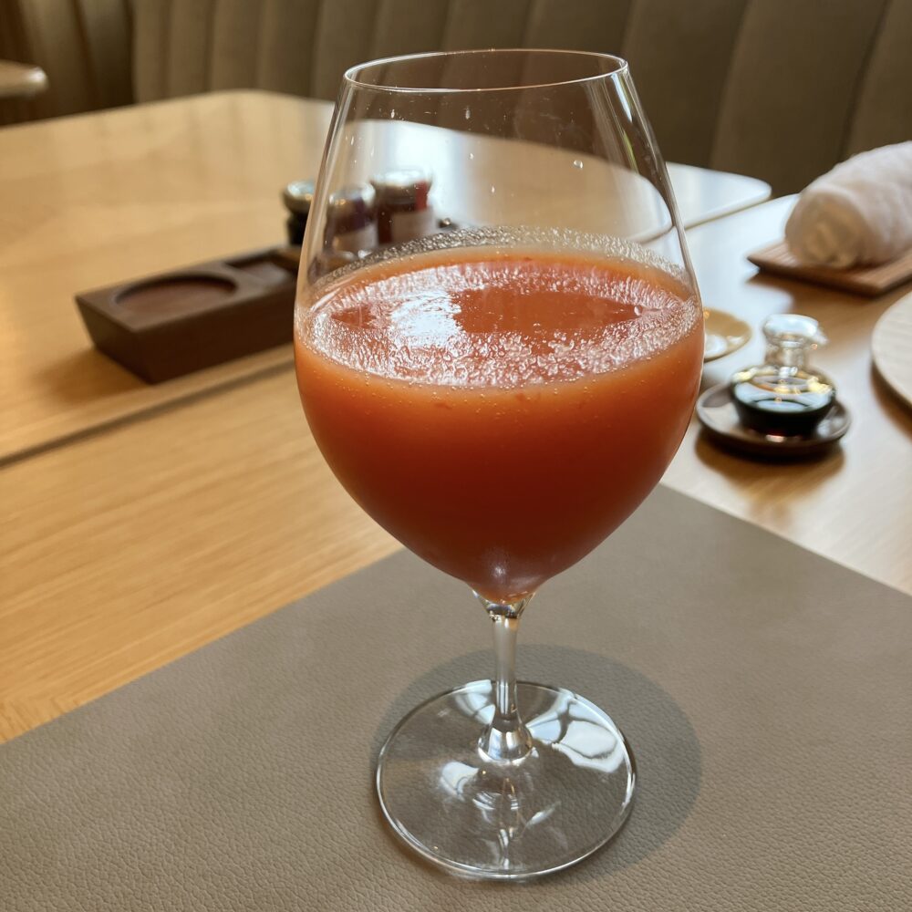 帝国ホテル京都の朝食で提供される、ワイングラスに入った色鮮やかなにんじんとりんごのフレッシュベジタブルジュース