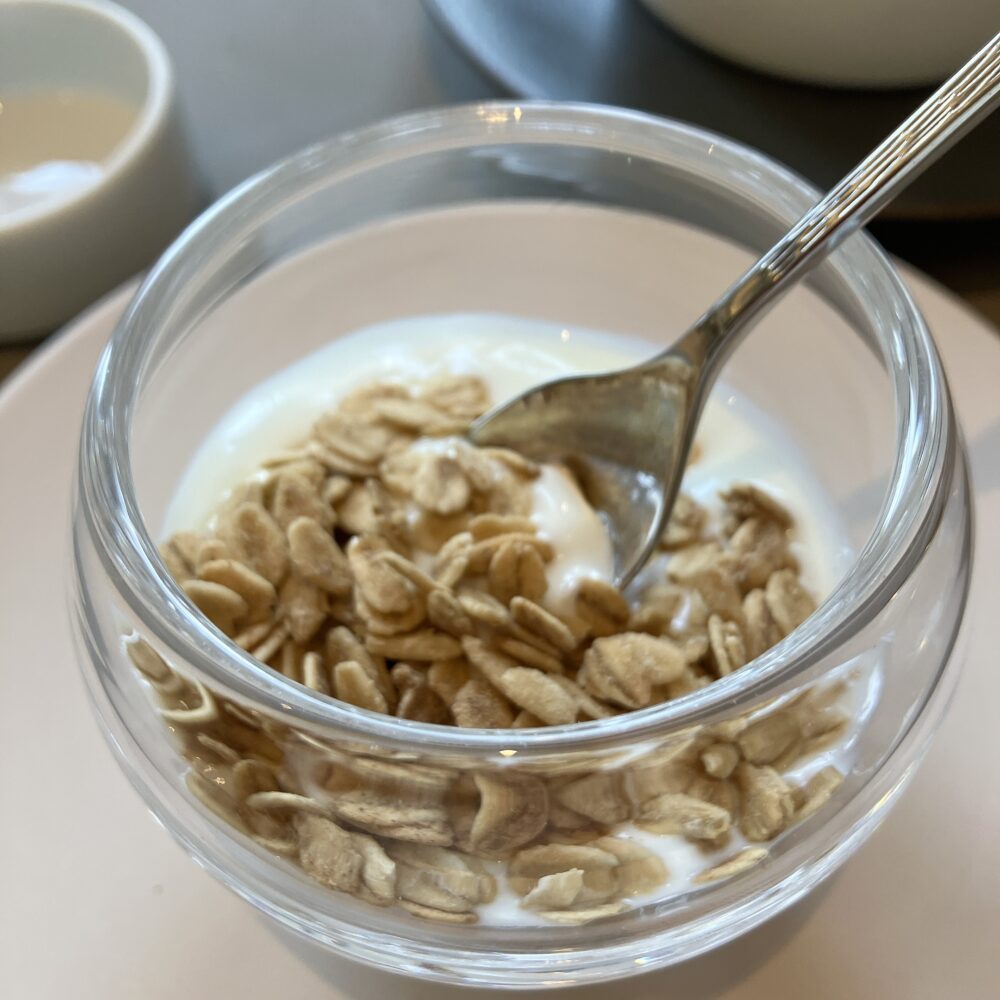 帝国ホテル京都の朝食で提供される、ガラスの器に入ったオーガニックヨーグルトとたっぷりのシリアル（グラノラ）