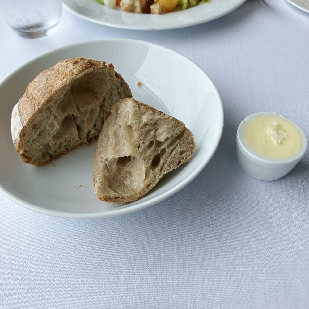 パークハイアット東京 ニューヨークグリルで提供された、外側がパリッと焼き上げられた艶やかなパンとバター。シンプルながら手が止まらないクオリティ。
