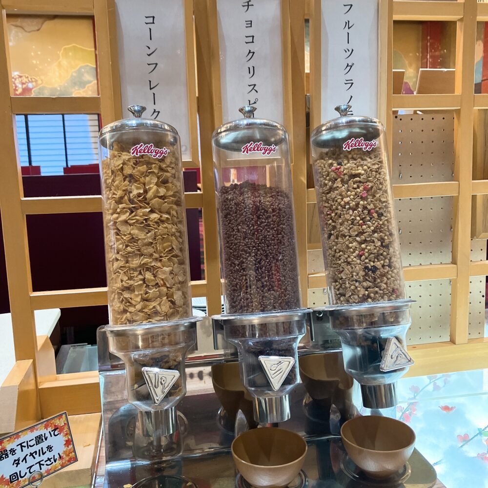 朝食バイキング会場に設置された、コーンフレーク、チョコクリスピー、フルーツグラノラの3種類のケロッグシリアルディスペンサー。