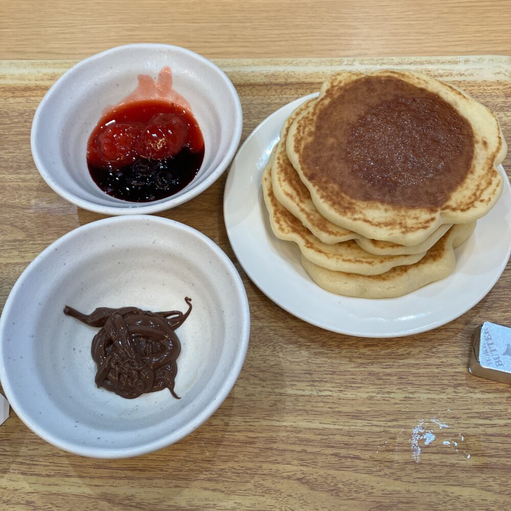 何枚も重ねられたパンケーキと、ストロベリージャム、チョコレートクリーム、バター。