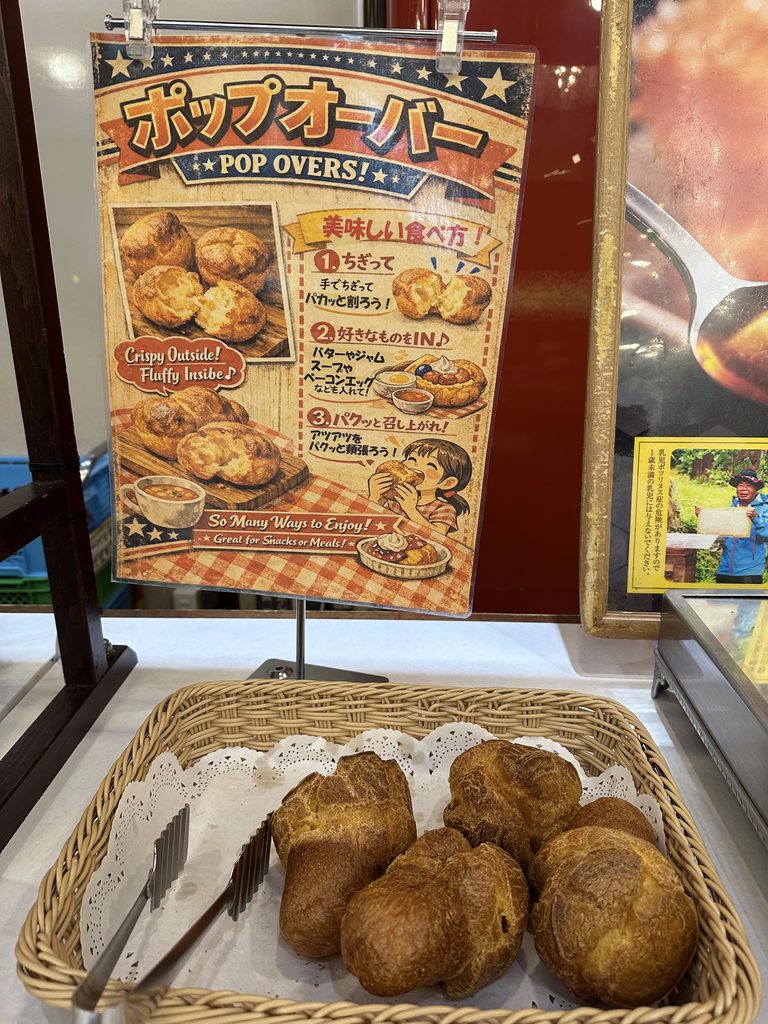 バスケットに盛られた焼き立てのポップオーバーと、「美味しい食べ方」が書かれた案内看板。